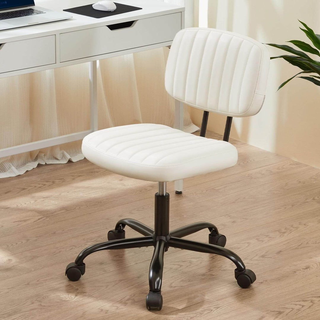 A white, padded, rolling swivel computer task chair without armrests, positioned on a hardwood floor in front of a desk.